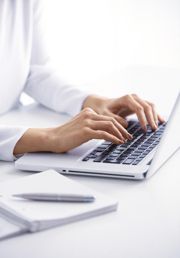 Close-up of businesswoman's hand typing on the keyboard while sitting at office desk.